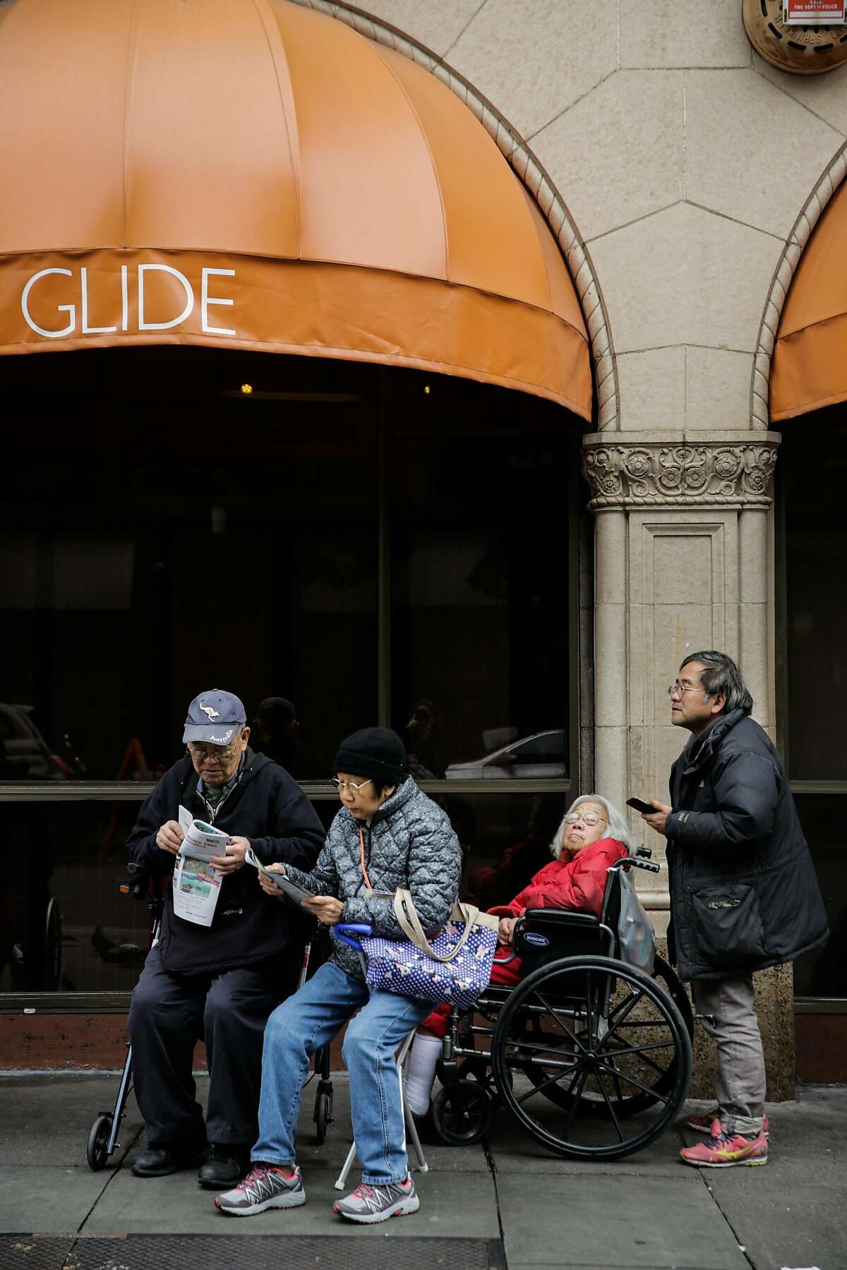 People wait outside Glide Memorial Church ahead of a free Christmas Eve lunch hosted by House of Prime Rib in San Francisco, Calif., on Sunday, Dec. 24, 2017.