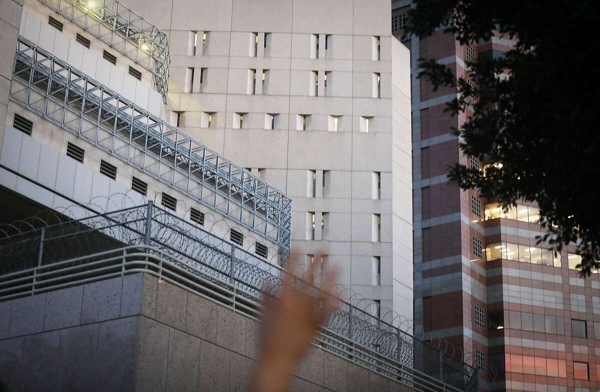 A protestor waves towards cell windows (CENTER and TOP C) where ICE detainees are being held in upper floors of the Metropolitan Detention Center on June 14, 2018 in Los Angeles. Protestors at one point chanted 'You Are Not Alone' towards the detained as the detainees flashed lights back from the small cell windows inside the detention center. U.S. Immigration and Customs Enforcement recently arrested 162 undocumented immigrants during a three-day operation in Los Angeles and surrounding areas. 