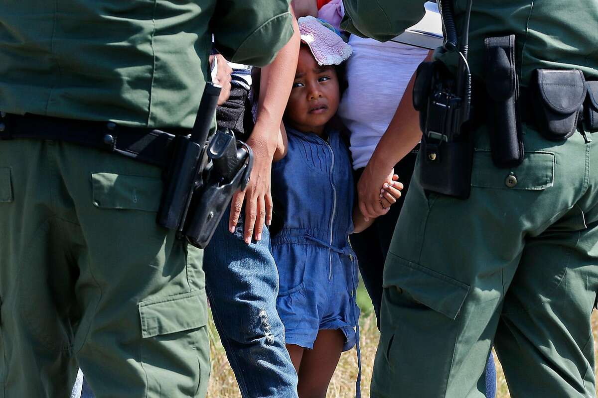 U.S. Border Patrol agents question adult and child immigrants near Anzalduas Park, southwest of McAllen, Texas.