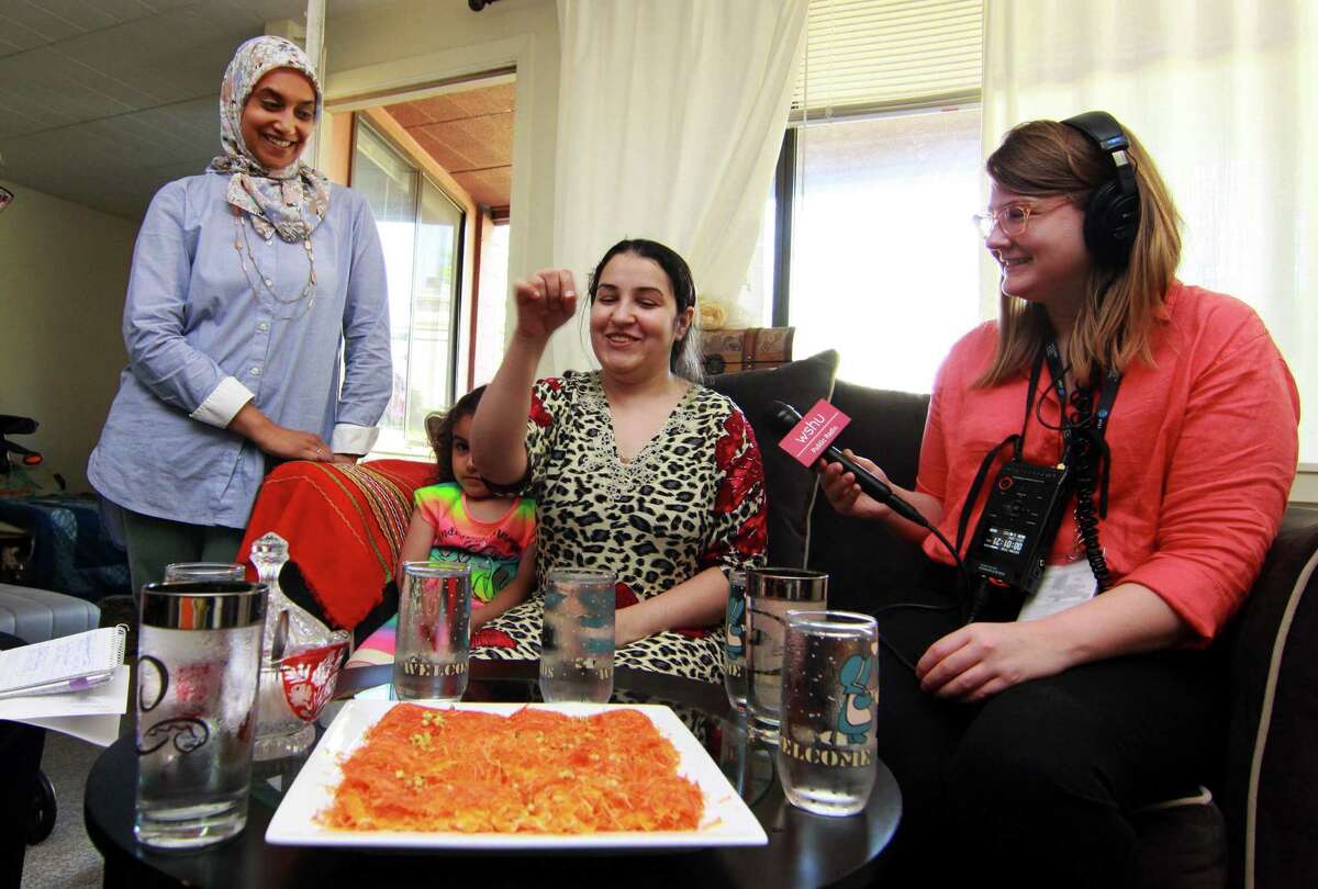 Zainab Al-Qaderi, a refugee chef from Iraq, seated in center, serves kanafeh, a Middle Eastern dessert, at her home in New Haven on Tuesday. With Zainab at left is Sumiya Khan of Sanctuary Kitchen at CitySeed, Zainab’s daughter Ritaj, 4, and at right is WSHU reporter Cassandra Basler. Al-Qaderi will serve the dessert on Saturay at the World Refugee Day Festival.