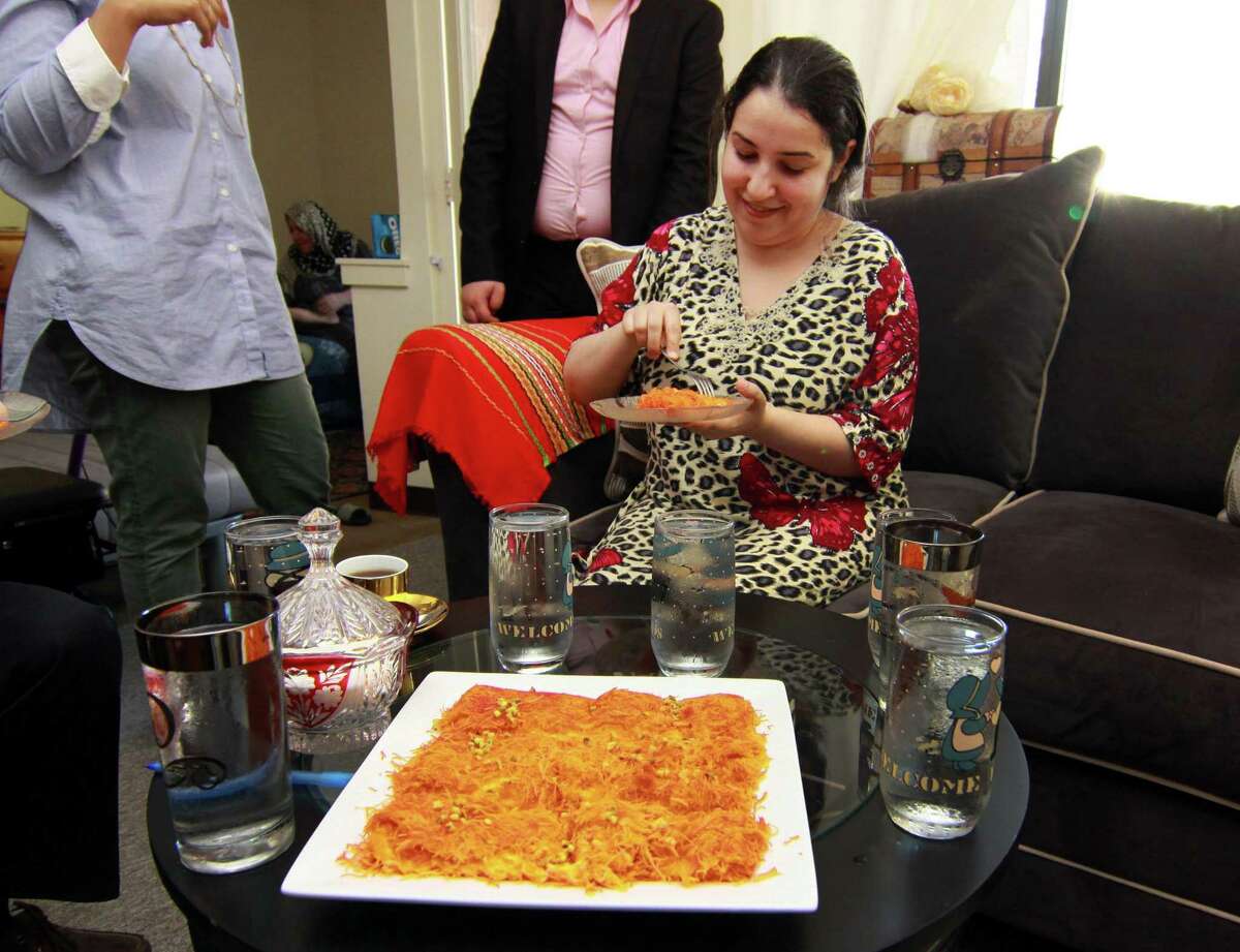 Zainab Al-Qaderi, a refugee chef from Iraq, tastes kanafeh, a Middle Eastern dessert which she made, at her home in New Haven on Tuesday. Al-Qaderi will serve the dessert on Saturday at the World Refugee Day Festival.