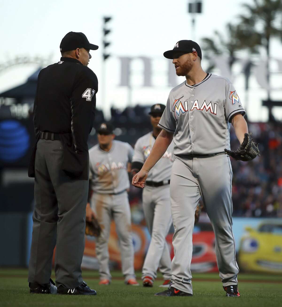 Miami Marlins pitcher Dan Straily, right, speaks with home plate umpire Andy Fletcher after Straily hit San Francisco Giants' Buster Posey with a pitch and was ejected by Fletcher during the second inning of a baseball game Tuesday, June 19, 2018, in San Francisco. (AP Photo/Ben Margot)