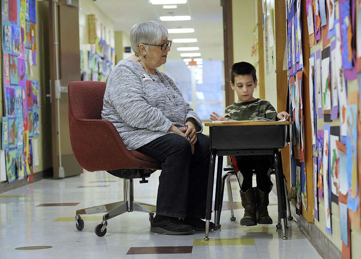 Grace Scalera Manning reads with kindergartner Max Ellenberg, 6, in the hallway at Consolidated School May 10, 2017, in New Fairfield, Connecticut. Such volunteering signals that seniors are redefining their retirements.