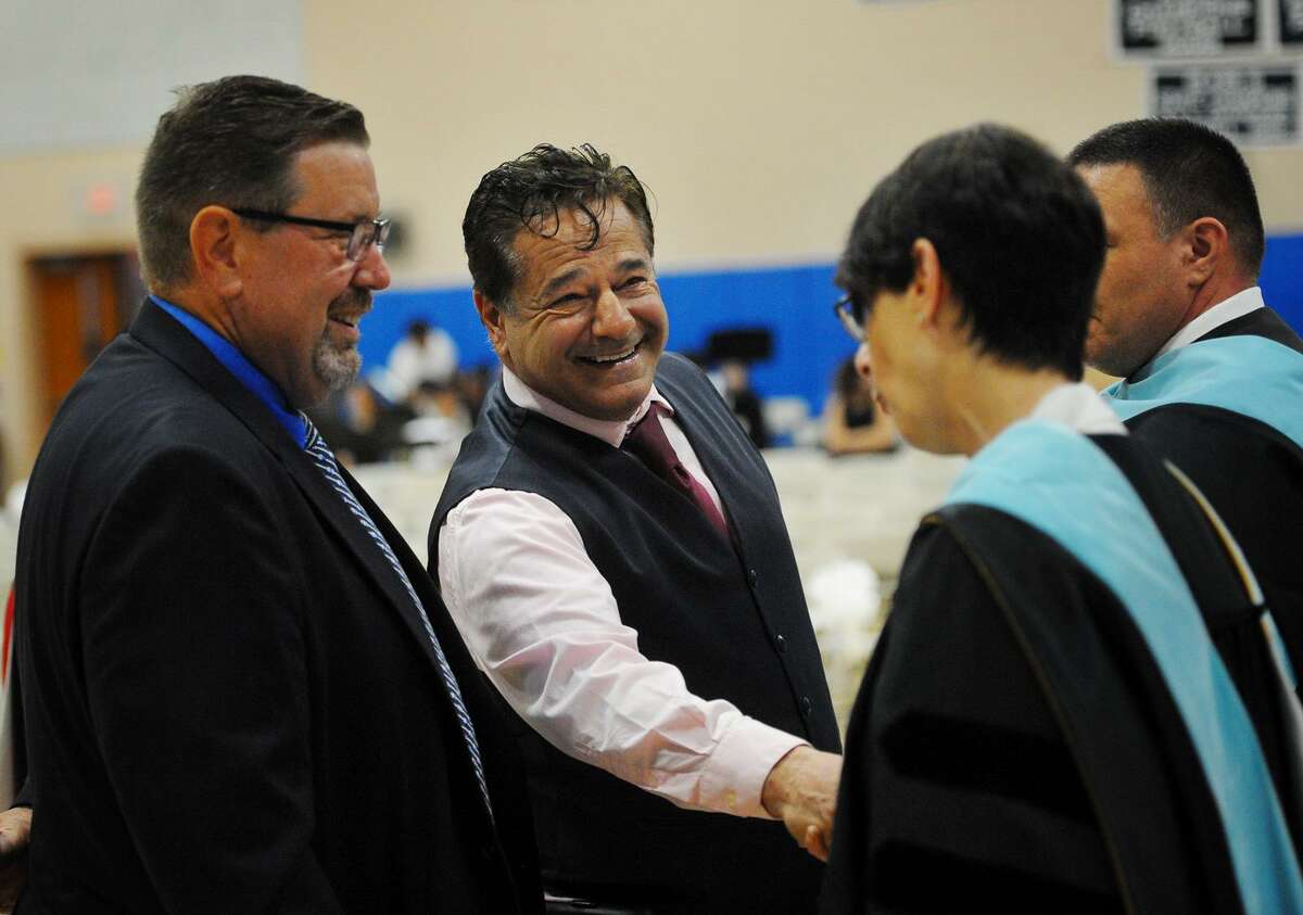 Ansonia Mayor David Cassetti shakes hands with Superintendent of Schools Carol Merlone while Chris Phipps, a Board of Education member and Assistant Supt. of Schools Joseph DiBacco look on during Monday’s Ansonia High School Commencement.