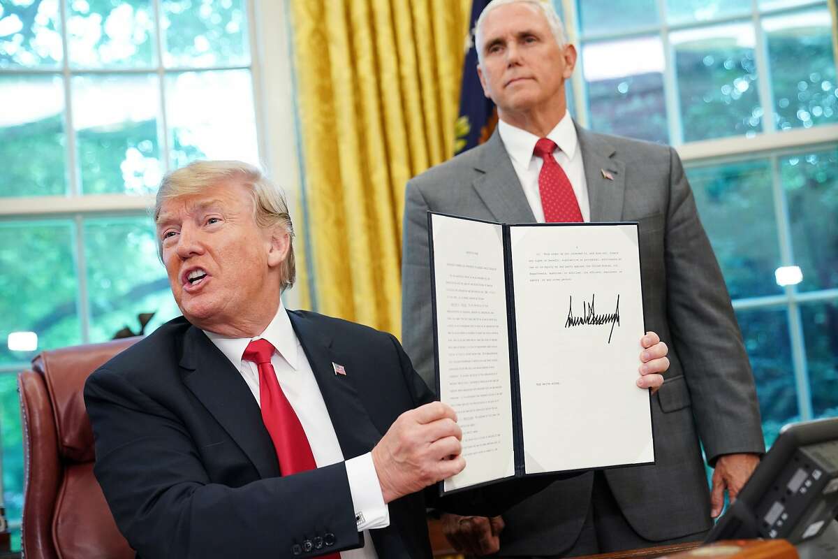 Watched by Vice President Mike Pence, US President Donald Trump shows an executive order on immigration which he just signed in the Oval Office of the White House on June 20, 2018 in Washington, DC. US President Donald Trump on Wednesday signed an executive order aimed at putting an end to the controversial separation of migrant families at the border, reversing a harsh practice that had earned international scorn."It's about keeping families together," Trump said at the signing ceremony. "I did not like the sight of families being separated," he added. 