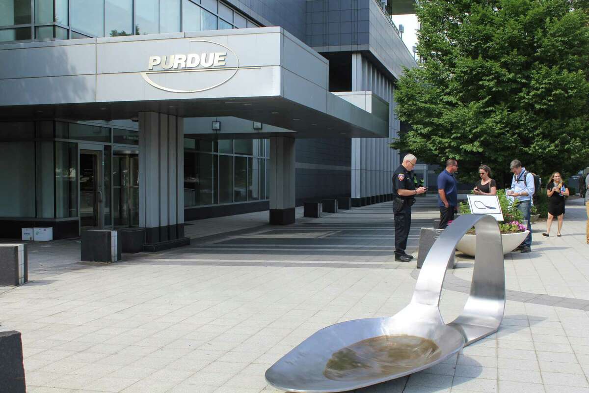 Protesters Friday placed a colossal steel spoon singed to symbolise burnt heroin in front of the Stamford, Conn. headquarters of Purdue Pharma.
