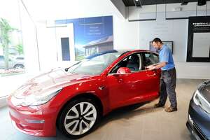 Dom Vivona of Old Greenwich inspects a Tesla Model 3 on display inside the Tesla Gallery at 340 Greenwich Ave., Greenwich, Conn., Friday, June 22, 2018. Vivona said his name is on the waiting-list to acquire a 4-wheel drive version of the vehicle. According to Car & Driver Magazine, the sale price for the electric rechargable battery-powered Model 3 is $36,000, it does 0- 60 mph in 5.1 seconds with a top speed of 141 mph and the rear-wheel-drive models travel about 220 miles on a single charge.
