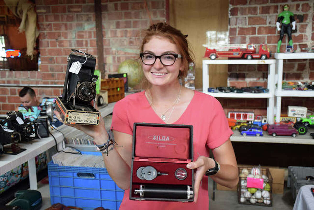 Mackenzie Dixon displays an antique camera and what she and her father, Tim, suspect is an ophthalmologist’s device Saturday during the Grafton Riverside Flea Market at The Loading Dock.