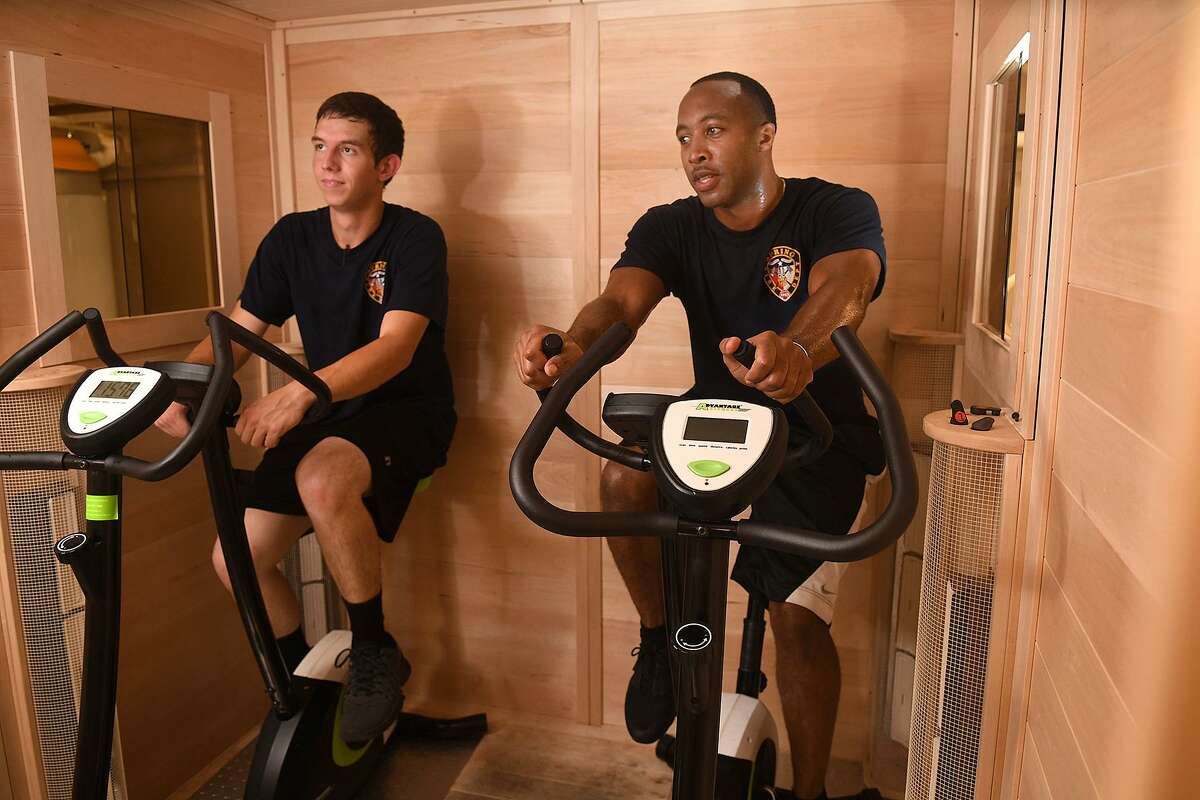 Cadet firefighters Colton Allen, 20, left, and Bradley Whitlock, 32, of Spring Fire Dept. Station 70, ride exercise bikes in the medical grade dry (detoxification) sauna that crew members use after responding to a fire call at the station on June 19, 2018. (Jerry Baker/For the Chronicle)