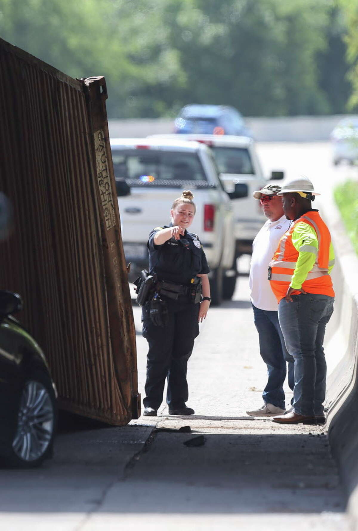 HPD officers and crew members work on a scene where a trailer truck struck the Houston Avenue bridge and its container fell onto a sedan vehicle on Monday, June 25, 2018, in Houston. Both drivers are not injured.