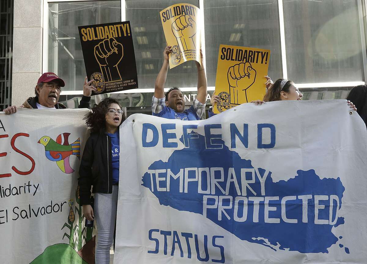 Supporters of temporary protected status immigrants hold signs and cheer at a rally before a news conference announcing a lawsuit against the Trump administration.