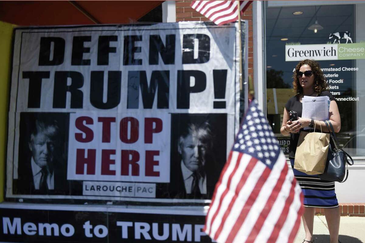 Erica Fruin stops by the LaRouche PAC information stand set up near the U.S. Post Office in the Cos Cob section of Greenwich, Conn. Tuesday, June 26, 2018. The political action committee, named after Lyndon LaRouche, asks to end the "coup" against President Trump, support China's One Belt One Road Initiative, and support LaRouche's economic policies reinstating the Glass?–Steagall banking separation act and returning to a national banking system.