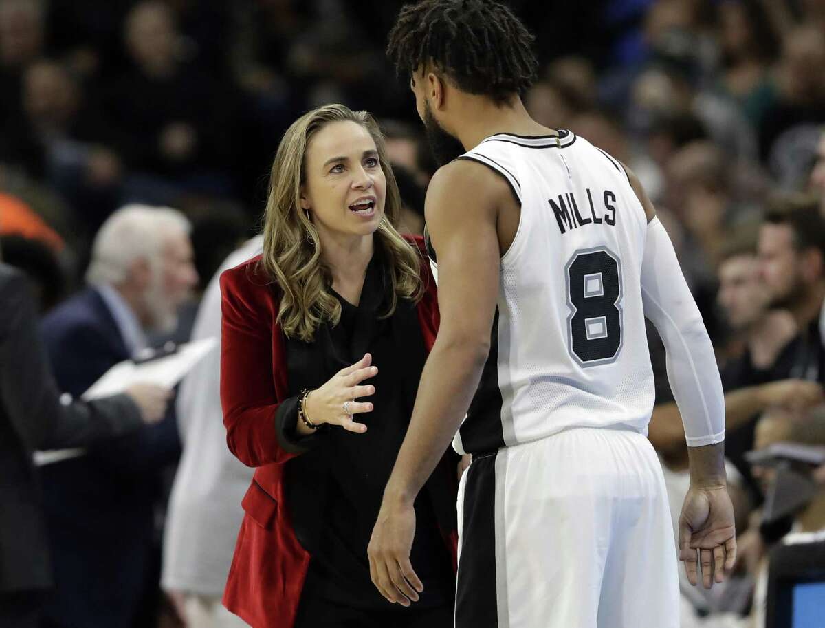 San Antonio Spurs assistant coach Becky Hammon, left, talks with guard Patty Mills (8) during the second half of an NBA basketball game against the New York Nets, in San Antonio. A diversity report released shows the NBA continues to lead the way in men's professional sports in racial and gender hiring practices.