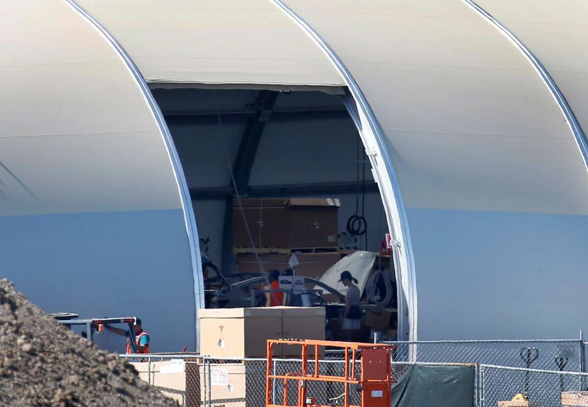 Factory workers assemble a car inside a temporary building in a back lot of the Tesla manufacturing plant in Fremont, Calif. on Wednesday, June 27, 2018. Tesla is assembling the new Model 3 sedan in the tent-like structure to meet demand and deadlines.