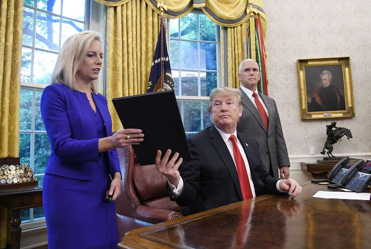 President Donald Trump gives a signed executive order to keep families together at the border to Homeland Security Secretary Kirstjen Nielsen, left, in the Oval Office of the White House in Washington, D.C., on June 20, 2018. (Olivier Douliery/Abaca Press/TNS)