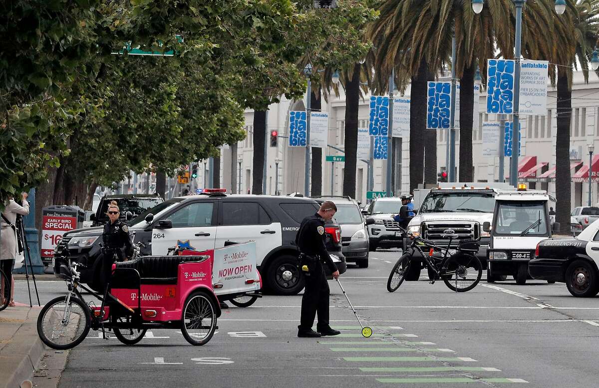 A police officer measure the scene of the crash after a hit and run accident involving a pedicab and vehicle on the Embarcadero in San Francisco on Wednesday, June 27, 2018.