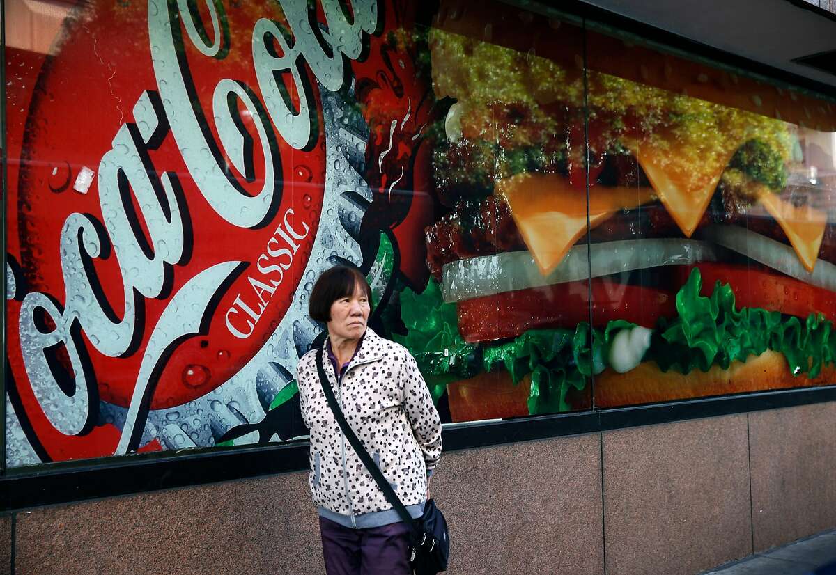 A woman walks past an advertisement for soda outside of a fast food restaurant on Eddy Street in San Francisco, Calif. on Wednesday, Nov. 2, 2016. Supporters and opponents have spent $30 million on Prop. V, the proposed one cent per ounce tax on sugary drinks, more than 23 other local ballot measures combined.