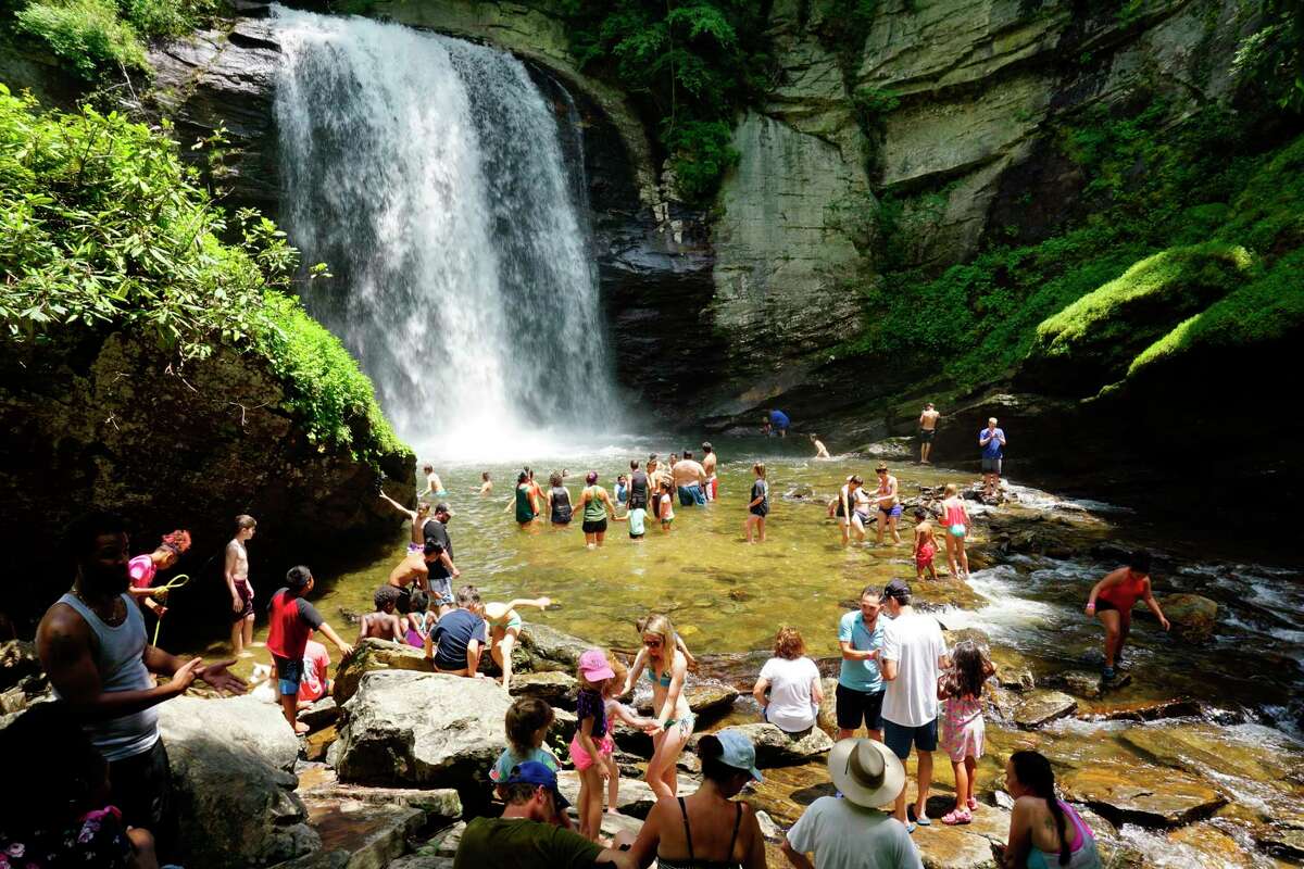 This May 18, 2018 photo shows swimmers wading in at the base of Looking Glass Falls, located in the Pisgah National Forest, between Brevard, N.C., and the Blue Ridge Parkway. Known as "The Land of the Waterfalls," Transylvania County boasts more than 250 waterfalls that attract visitors every year. (Hillary Speed via AP)