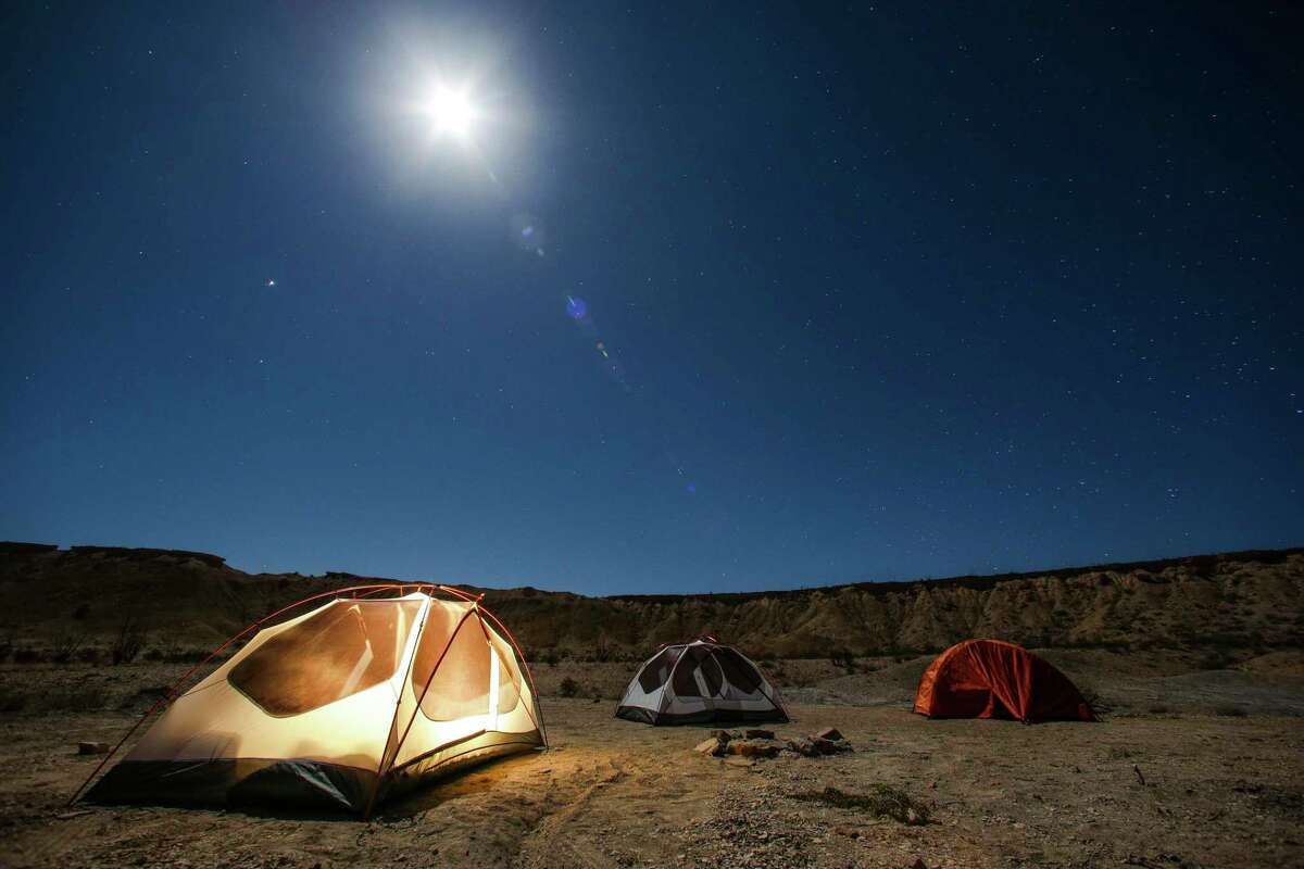 The full moon rises above tents at a campsite outside Big Bend National Park.