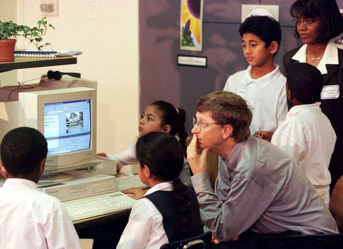 Bill Gates looks over computer work by students in a third-grade classroom 20 years ago.