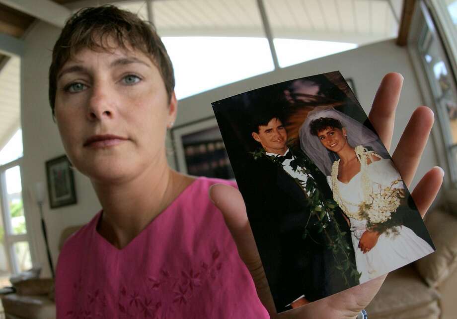 Michelle Hobus, formerly Michelle Scully, holds a wedding picture of herself and her late husband, John Scully, at her home in Hawaii Kai, Hawaii Monday, June 30, 2003. Ten years ago a gunman entered a high-rise in San Francisco and killed eight people, including John Scully, who used his 6-foot-4 frame as a shield to protect his wife. The gunman wordlessly opened the door and shot John six times and Michelle once. (AP Photo/Ronen Zilberman) Photo: Ronen Zilberman / Associated Press 2003