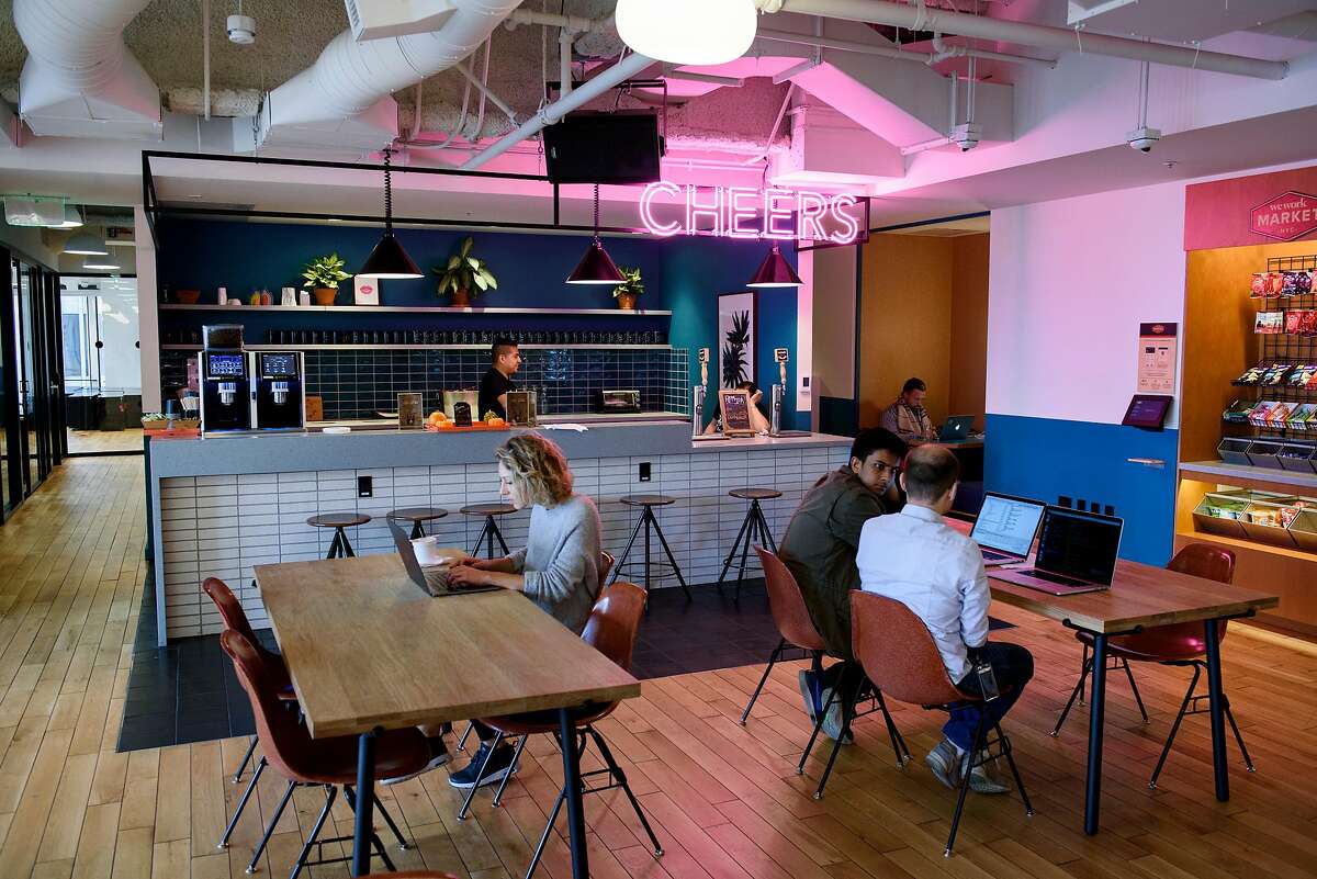 A bar area is seen in the background as WeWork members work in a common room at the Embarcadero WeWork offices in San Francisco, Calif, on Thursday October 19, 2017.