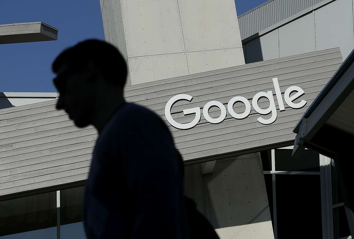 FILE - In this Nov. 12, 2015, file photo, a man walks past a building on the Google campus in Mountain View, Calif. Voters in a Northern California city will decide whether Google and other tech companies should help pay for the traffic headaches and other problems that have arisen as their workforces have swelled during the past decade. The city council in Mountain View, California, voted Tuesday, June 26, 2018, to place a measure on the November ballot asking residents to authorize taxing businesses between $9 and $149 per employee. (AP Photo/Jeff Chiu, File)
