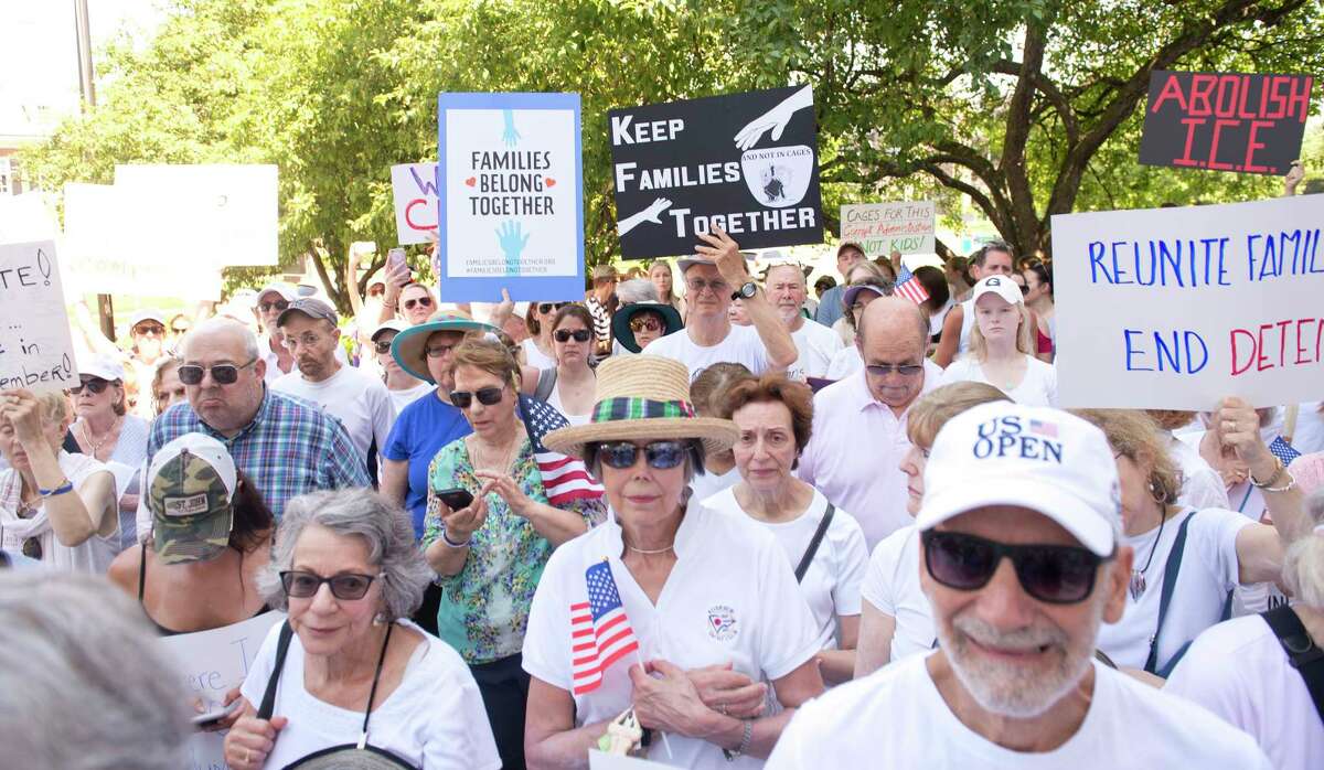 Protesters hold signs during a rally at Greenwich Town Hall, one of hundreds around the country, to protest family separation at the border on Saturday, June 30, 2018.
