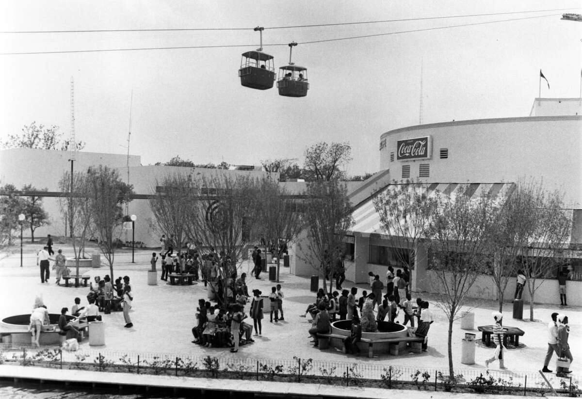 A HemisFair ’68 publicity photograph shows fairgoers outside the Coca-Cola Pavilion, with sky cars flying past the pavilion.