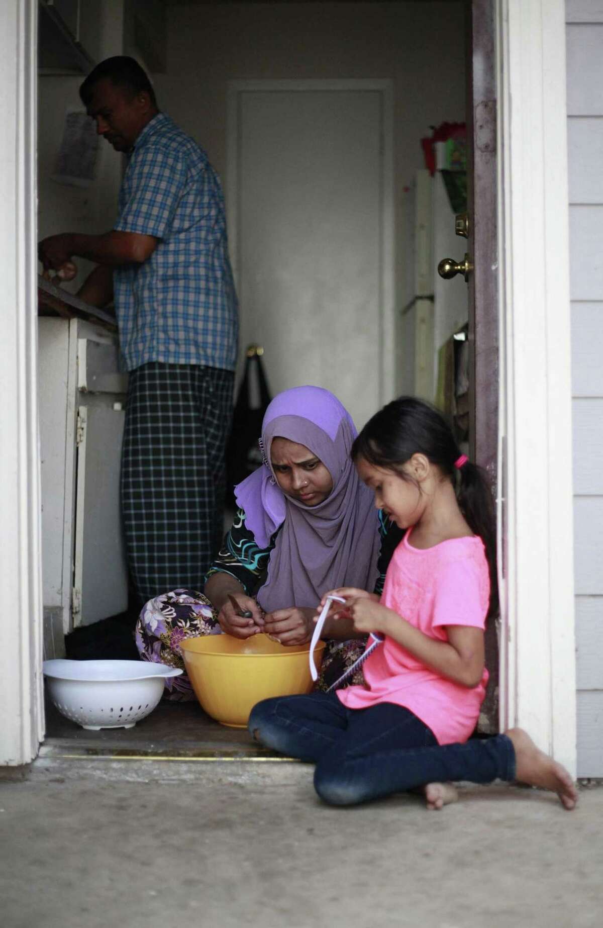 Siti Nur Anisha Binti Mohamad Rashid, 7, shows her mother Saidah Binti Yasin her heart-shaped sunglass as her mother and her father Mohamad Rashid Bin Nurislam prepare dinner.