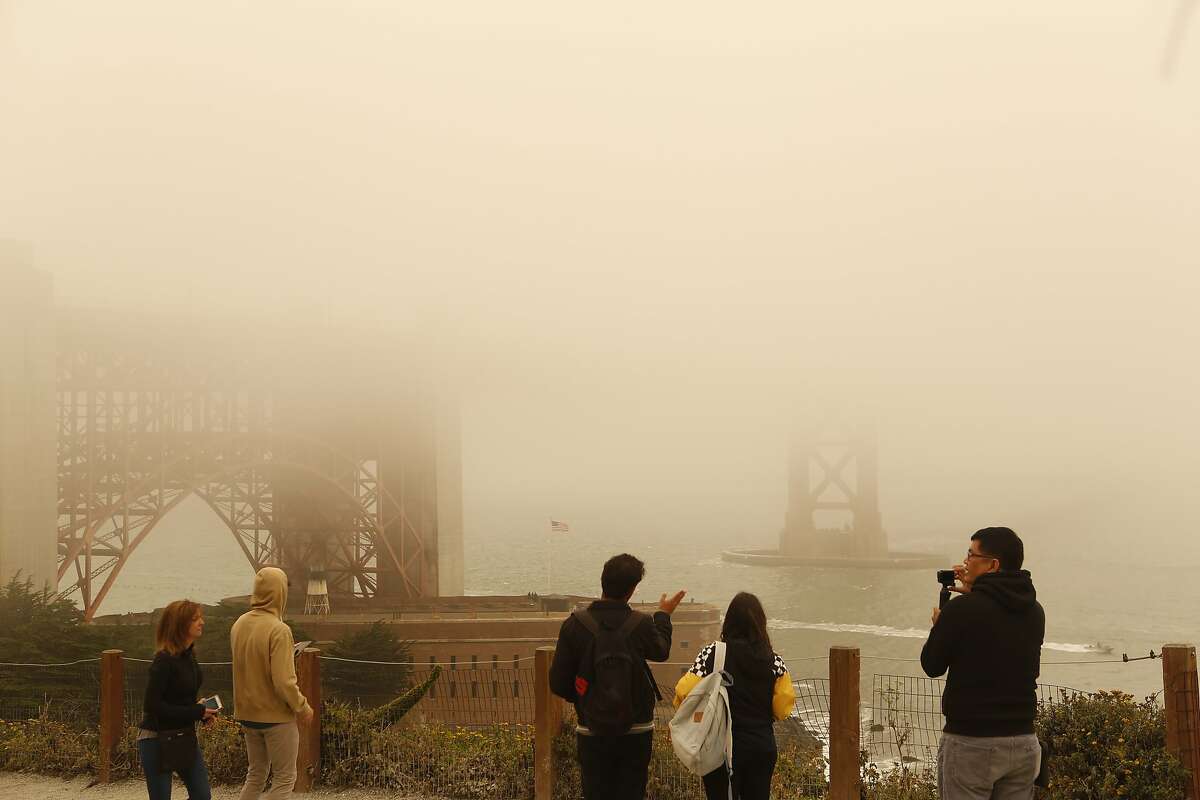 Tourists photograph the Golden Gate Bridge on Sunday, July 1, 2018 in San Francisco, Calif. Air quality in and around San Francisco has been visibly affected by the fires through the weekend.