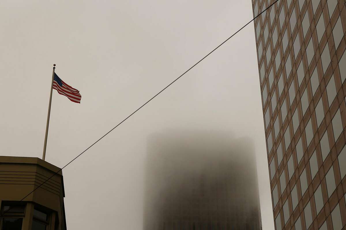 An American Flag blows in the wind around 555 California Street Building that is consumed in haze on Sunday, July 1, 2018 in San Francisco, Calif. Air quality in and around San Francisco has been visibly affected by the fires through the weekend.