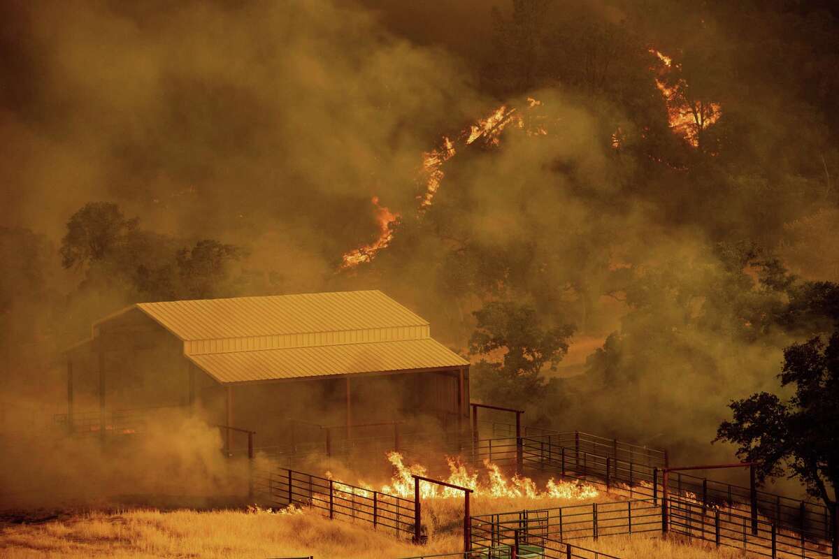 Flames rise around an outbuilding as the County fire burns in Guinda, Calif., Sunday July 1, 2018. Evacuations were ordered as dry, hot winds fueled a wildfire burning out of control Sunday in rural Northern California, sending a stream of smoke some 75 miles south into the San Francisco Bay Area.