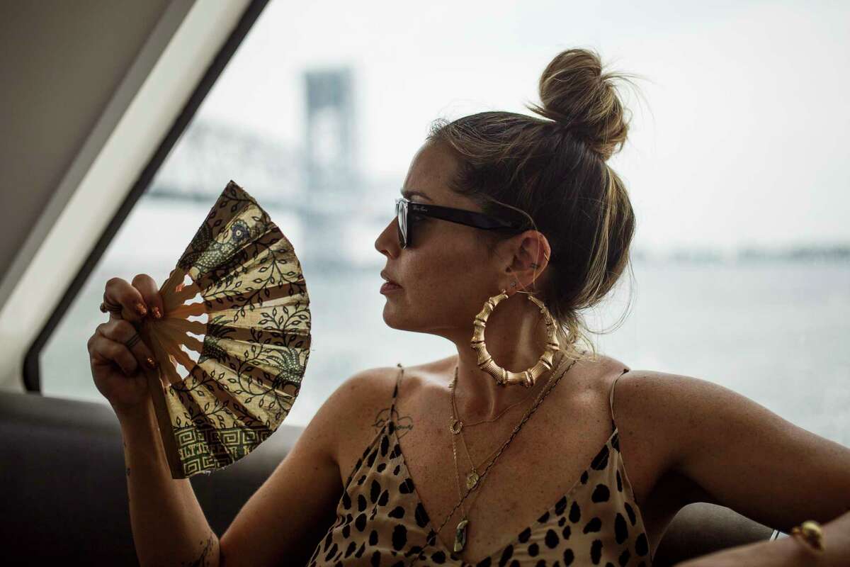 A woman fans herself to keep cool on the ferry en route to Rockaway Beach in New York, Sunday, July 1, 2018. (APPhoto/Andres Kudacki)