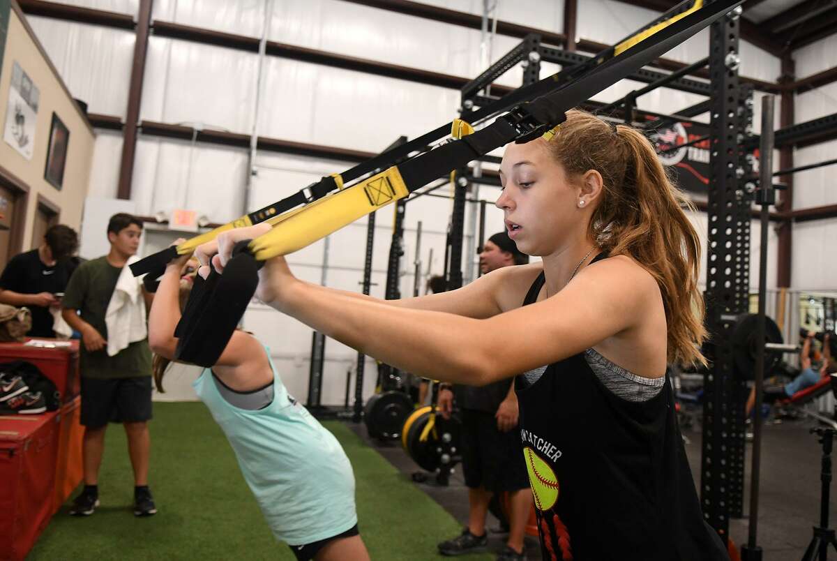 Haley Rust, 14, a 9th grader at Cy Woods High School, gets some TRX Biceps work in during a morning workout at Gym Cypress on June 18, 2018. (Jerry Baker/For the Chronicle)