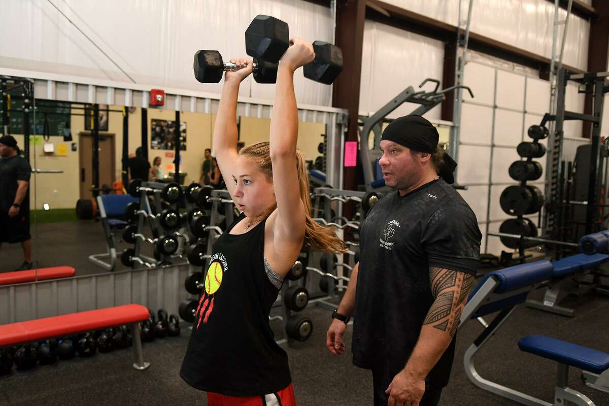 Haley Rust, 14, left, a 9th grader at Cy Woods High School, works on her dumbbell shoulder press in front of Damien Mockus, owner of Gym Cypress, during a morning workout at the gym on June 18, 2018. (Jerry Baker/For the Chronicle)
