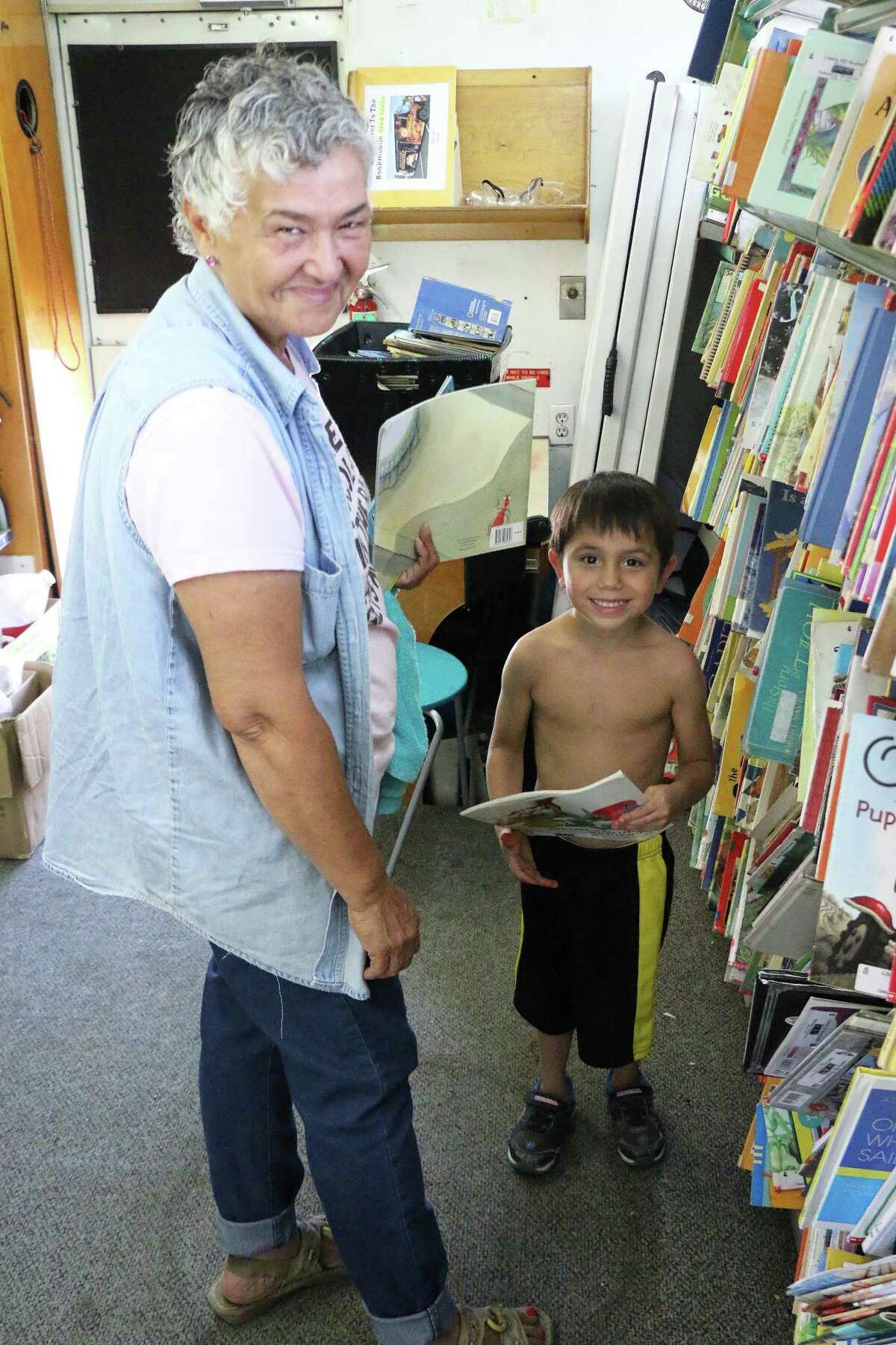 Dale Salazar and her grandson, Romeo Camacho, look through the books before he goes for a swim at the city water park.