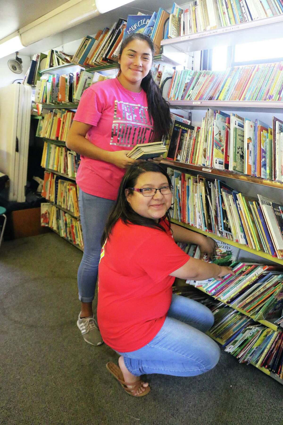 Senior Maribel Martinez and her friend junior Indira Samano straighten books before the next group of kids come onboard the LISD Bookmobile. The two have volunteered to work on the bus every summer since its inception four years ago.
