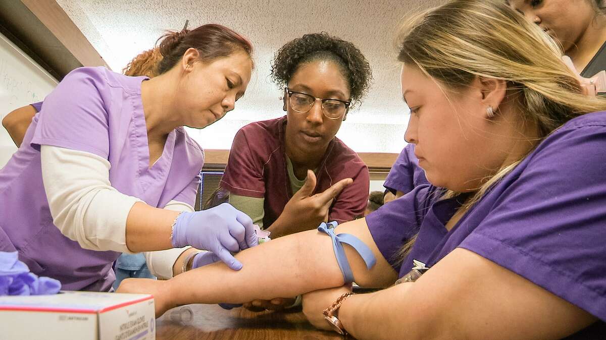 Harris County Department of Education adult learner Deysi Gonzalez prepares for the stick from fellow phlebotomy students.