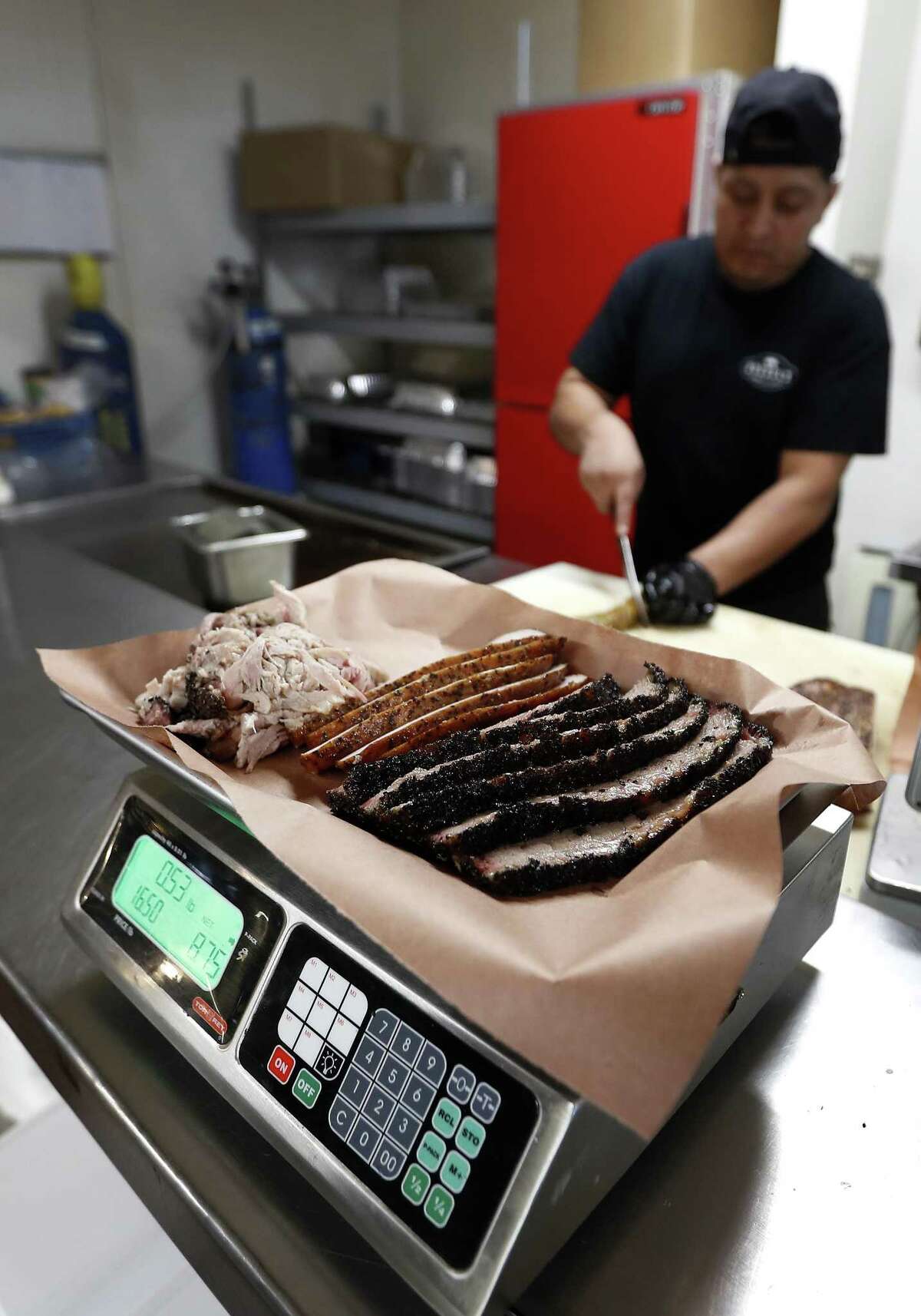 Russell Roegels of Roegels Barbecue Company, weighs meat on a scale behind the cash register, after Gudiel Tumax cuts it, Saturday, June 30, 2018, in Houston. Agriculture Commissioner Sid Miller has waged a war on BBQ joints, fining them for failing to follow rules the attorney general has said won?’t hold up in court. ( Karen Warren / Houston Chronicle )
