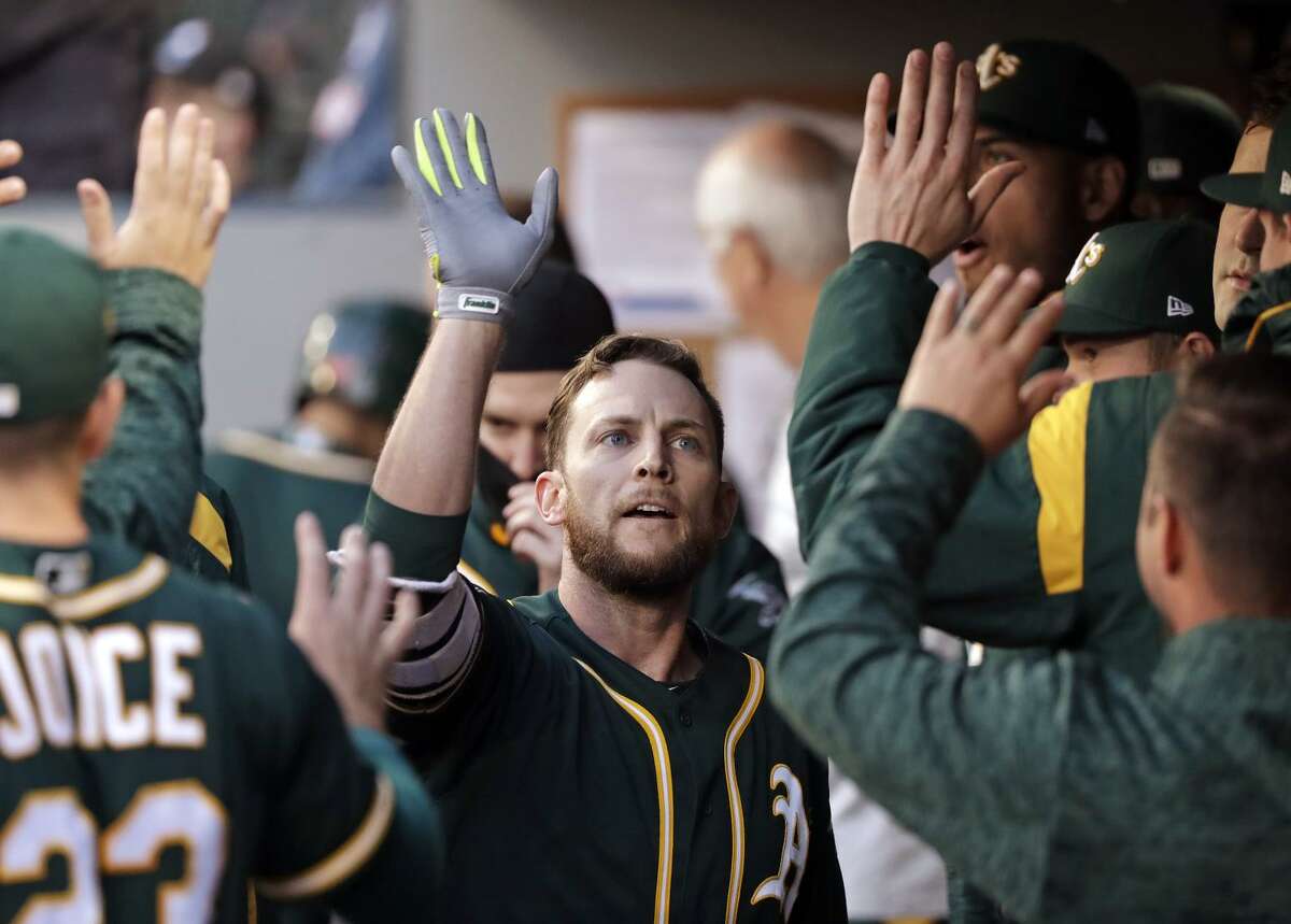 Oakland Athletics' Jed Lowrie is congratulated after hitting a home run against the Seattle Mariners in the first inning of a baseball game Tuesday, May 1, 2018, in Seattle.