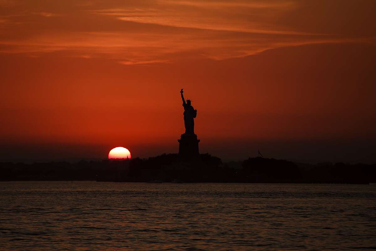 The sun sets behind the Statue of Liberty in New York, Sunday, July 1, 2018. (APPhoto/Andres Kudacki)