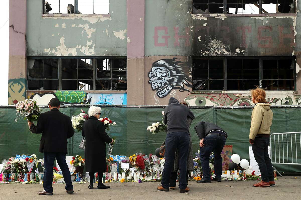 Family members of a Ghost Ship warehouse fire victim lay flowers at the scene on 31st Avenue in Oakland, Calif., on Monday, December 12, 2016.