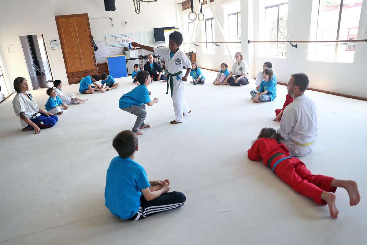 Jaja Young, 8, and Solomon Caplan, 9, practice a stunt as Master Rachael Evans (left) looks on during Superhero Stunts & Martial Arts Camp at Quantum Martial Arts in the Mission District of San Francisco, Calif. on Thursday, June 28, 2018.