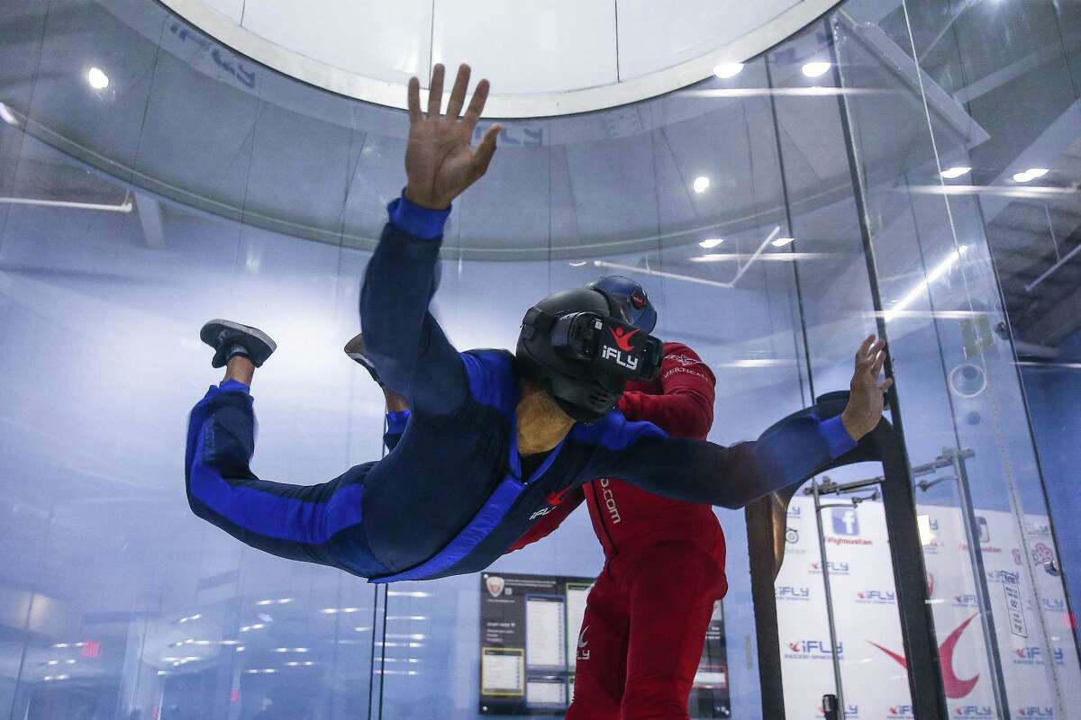 iFly instructor Ivan Buznego, right, helps lead instructor Marlon Mahoney, left, float in the wind tunnel while wearing a virtual reality headset for a 13,000 foot virtual free fall Monday, June 25, 2018. The headset plays a 360 degree video of professional skydivers jumping over the Swiss Alps, Dubai or Hawaii while customers float in the iFly wind tunnel. (Michael Ciaglo / Houston Chronicle)