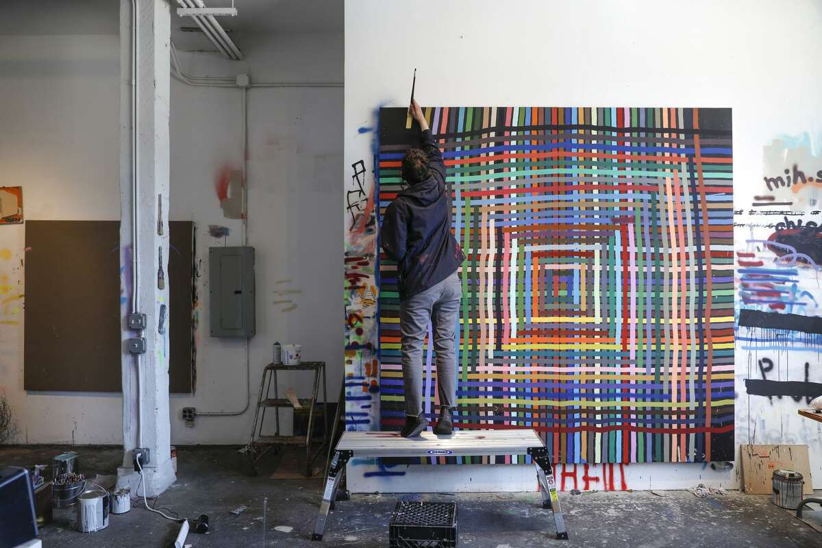 Alicia McCarthy works on a piece in her studio in Oakland, a maze-like colorful weave that is her signature style.
