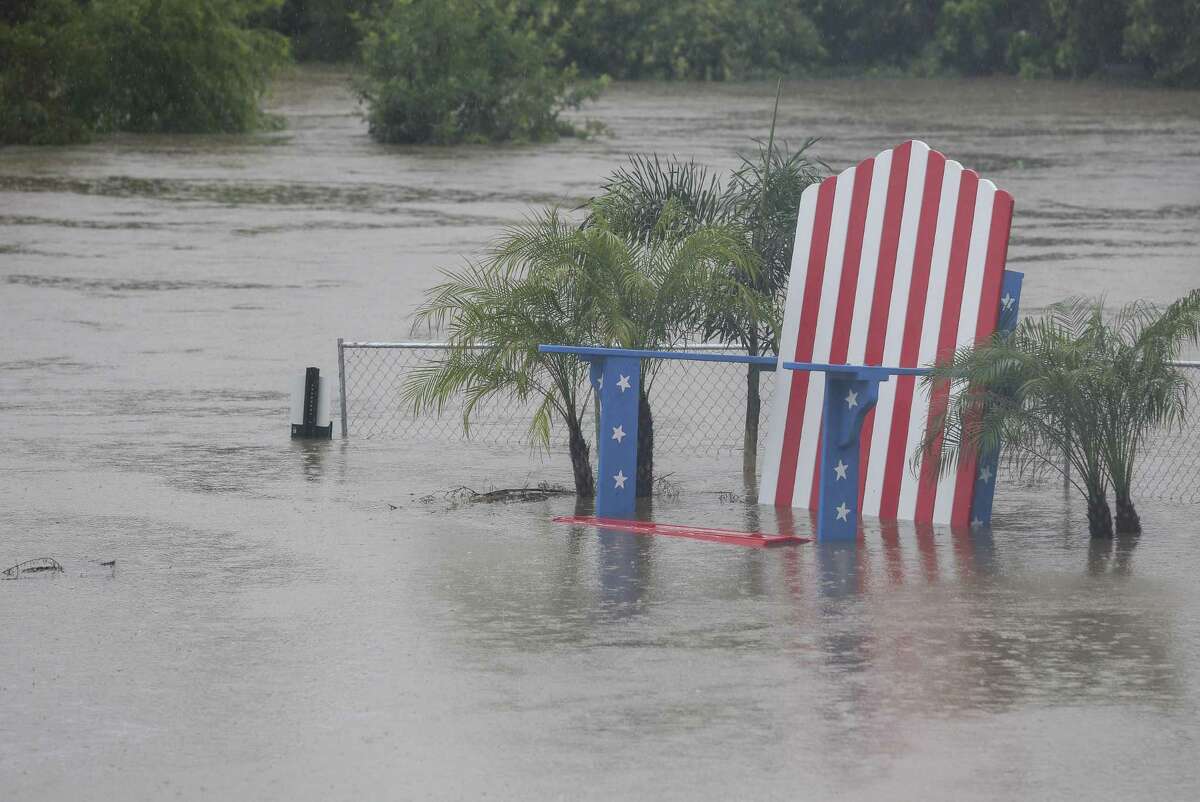A giant lawn chair, painted in patriotic colors and stars, is under Buffalo Bayou floodwater after heavy rainfall on Wednesday, July 4, 2018, in Houston. The Freedom Over Texas concert was cancelled after Buffalo Bayou flooded and compromised Eleanor Tinsley Park. ( Yi-Chin Lee / Houston Chronicle )