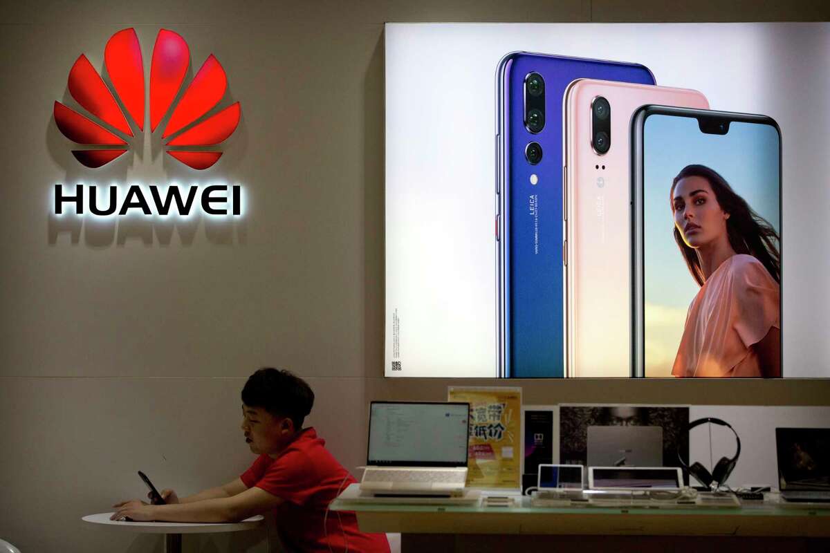 A sales clerk looks at his smartphone in a Huawei store at a shopping mall in Beijing Wednesday, July 4, 2018. 