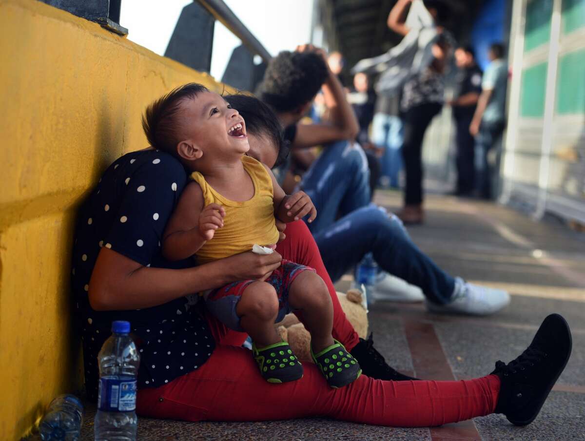 July 2, 2018 - Brownsville, Texas - Asylum seekers sleep on B/M Gateway bridge waiting to cross into U.S. from Mexico side. Ingrid Perdomo, 18 and her 1-year-old son Jose Luis play on bridge. She came with her companion Luis Miguel Luis Miguel Montimo, 32, 32 from Honduras where they made the difficult 3 month journey. He said he fled in fear and cries a lot with anxiety about losing his past. His ex-wife started dating a gang member and the gang torched his home killing his 2 children inside. He fled to mountains seeking safety where he met Ingrid and they had another child. When they first arrived they said they were told by border guards they would not get in until their child was an adult, possibly as a deterrent then went to stay with a cousin in Mexico for a few days but had kidnap threats and returned to bridge July 1. They were eventually allowed in late on July 2 to be processed for credible fear. If not for a small humanitarian group Asociacion Civil Ayudandoles a Triunfar a.c. run by Glady Canas from Mexico they would have not had blankets to sleep on, food, water, etc. Carol Guzy/for San Antonio Express-News