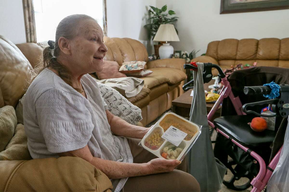 Kathy Warren, 59, smiles while holding the meal she received from Ariana Barber with Meals on Wheels at her home on Tuesday, June 26, 2018. Warren was diagnosed with multiple sclerosis in 2013.MARVIN PFEIFFER/mpfeiffer@express-news.net